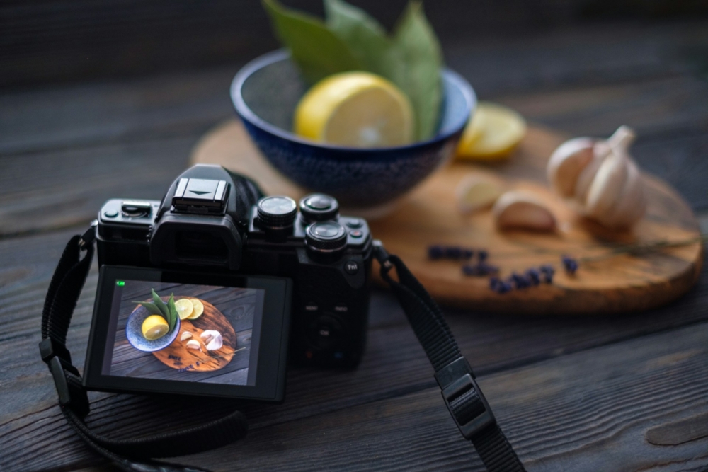 camera sitting on top of a wooden table with a still life of lemons and garlic