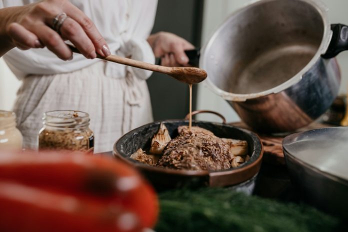Chef pouring gravy from a pot