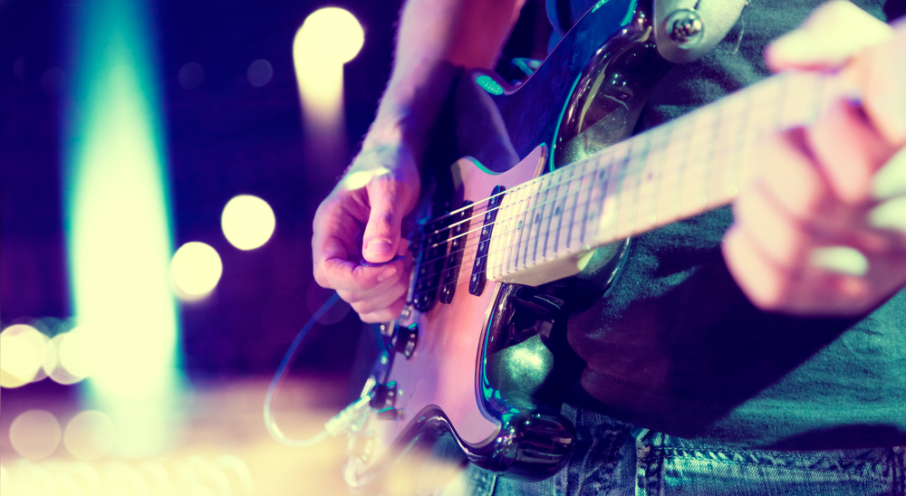 close up of hands playing an electric guitar