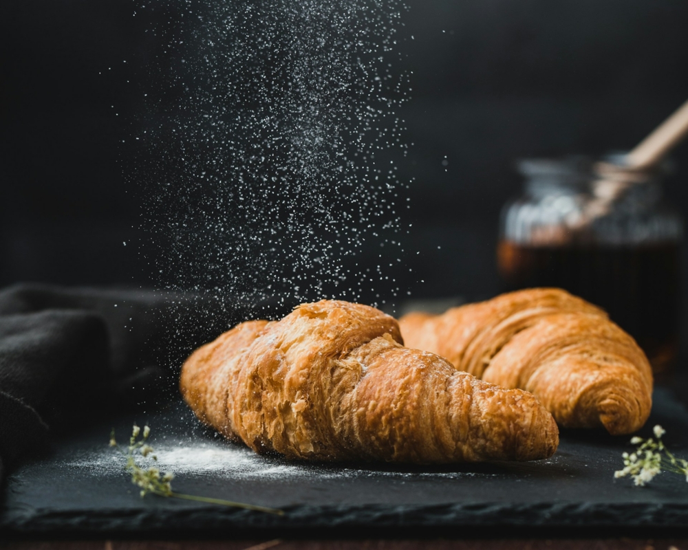 Croissant being dusted with sugar