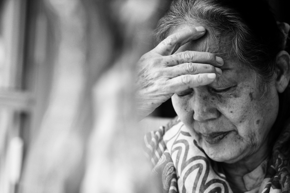 elderly woman covering her face with a hand BW