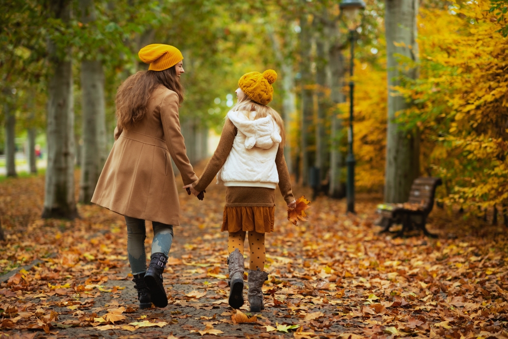 Mother and daughter walking down a trail in fall