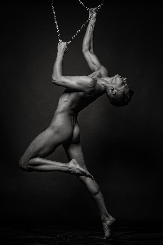 Nude male model posing with chains