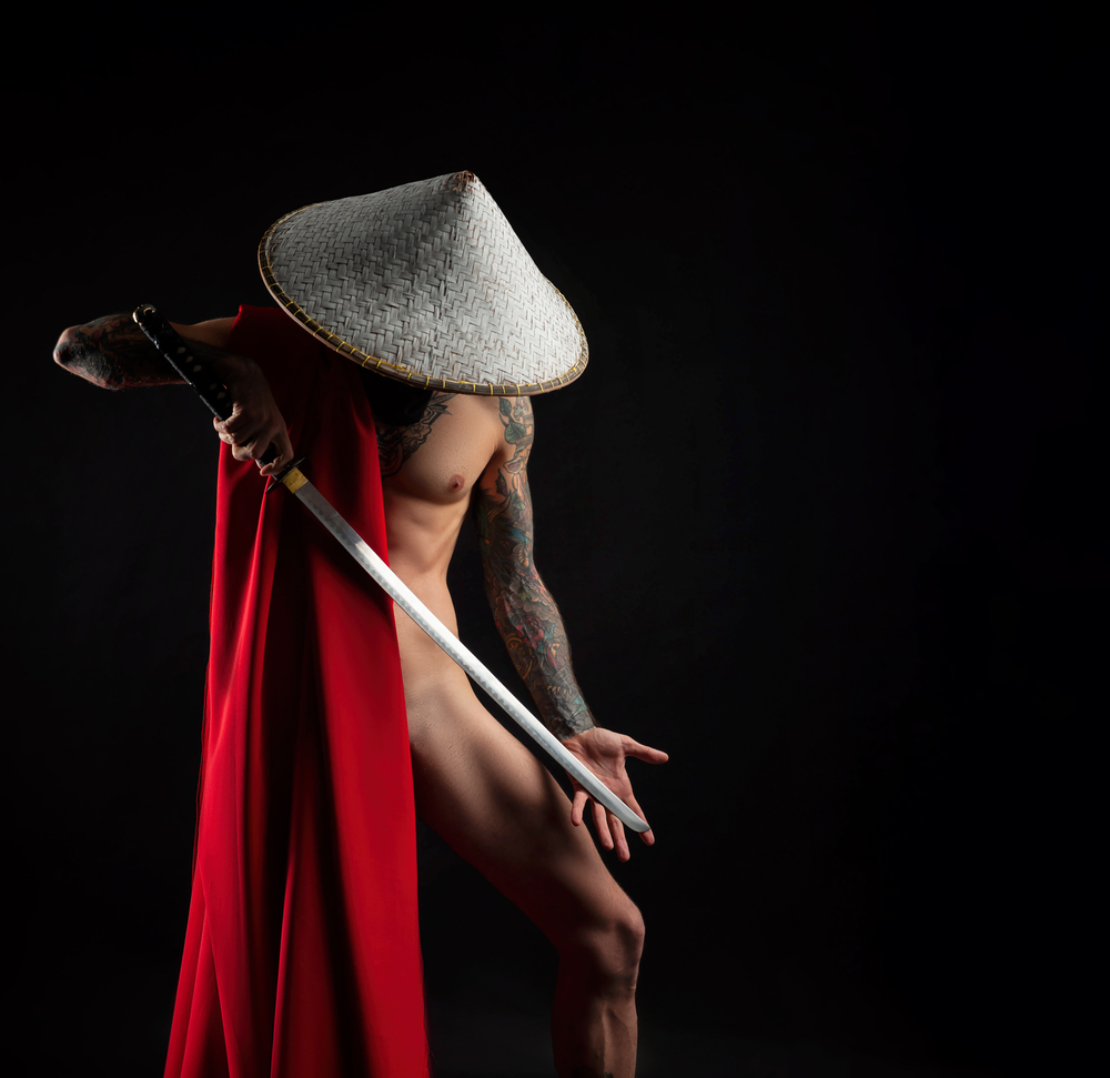 Nude man with red cape, in Asian hat with a katana