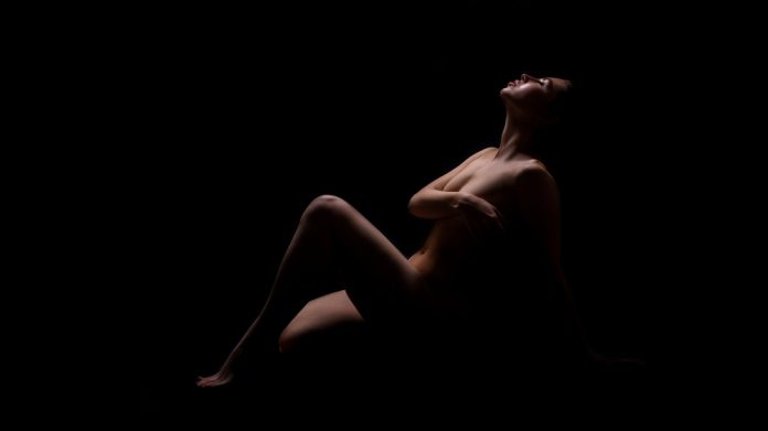 Nude woman reclining in a dark room
