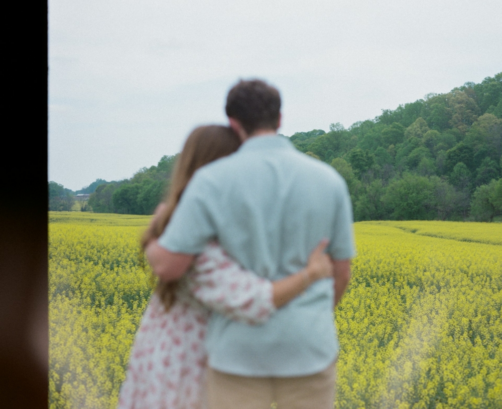 Out of focus couple in front of a yellow field of flowers