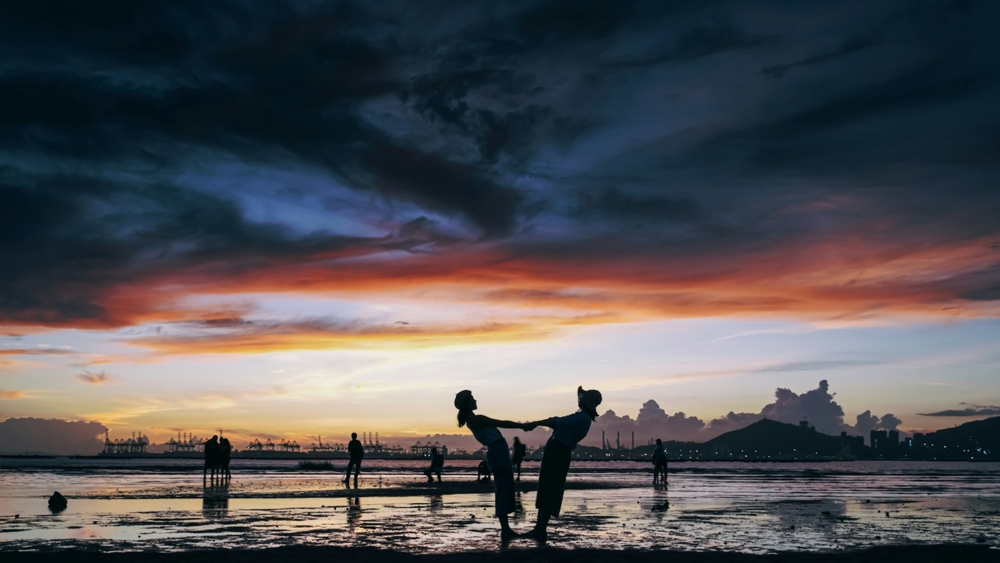 people playing in the water at sunset