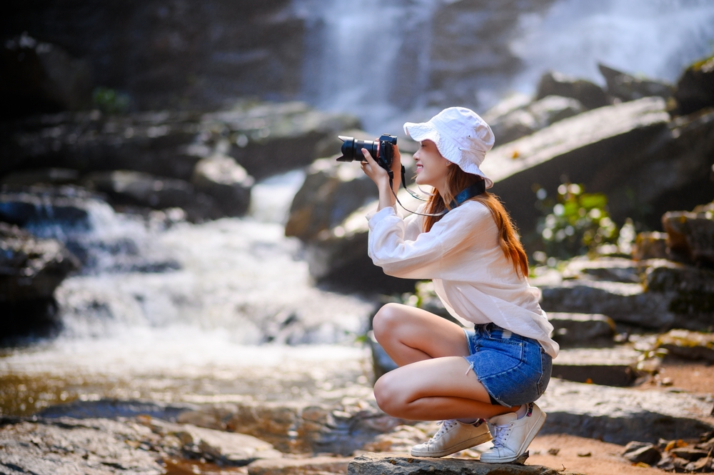photographer holding a camera near a waterfall