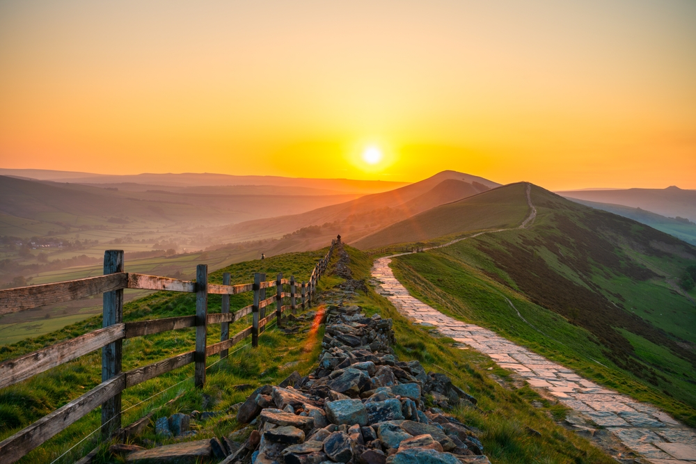 Stone footpath and wooden fence leading a long The Great Ridge in the English Peak District