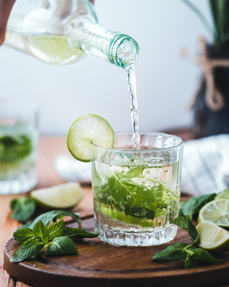 Water being poured into a glass with mint leaves