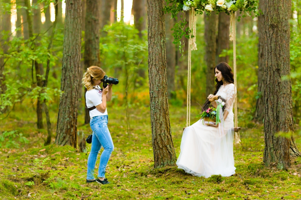 Wedding Photographer with a bride on a swing in the forest
